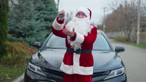 Positive Cheerful Santa Clause Bragging Car Keys Standing at Vehicle Outdoors Looking at Camera