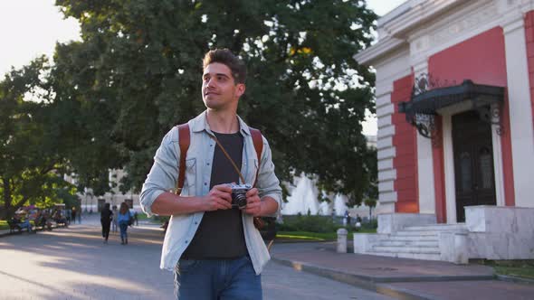 Attractive Young Handsome Man Tourist with Backpack Walking in City Center and Looking Around During