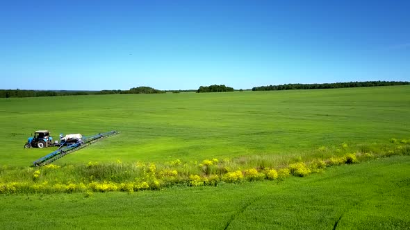 Tractor Sprinkling Chemicals Moves on Vast Green Field