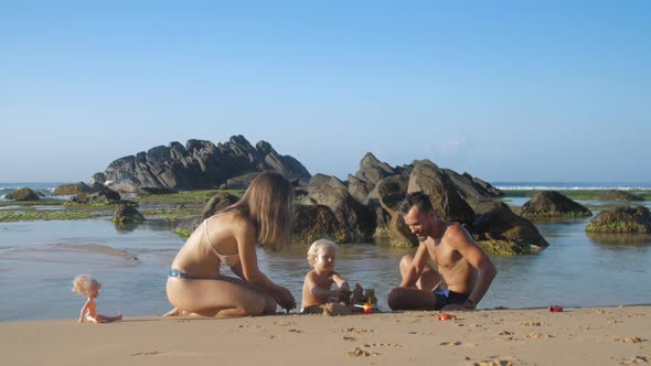 Husband Sculpts Sand with Wife and Child Swims in Ocean