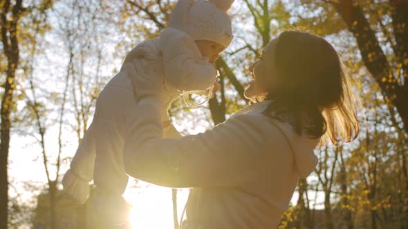 Baby in mom's arms in autumn park park