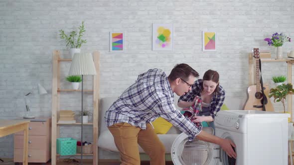 a Cheerful Couple of Newlyweds Are Engaged in Household Chores Using a Washing Machine