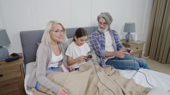 Senior Couple Playing Video Games Together with Granddaughter