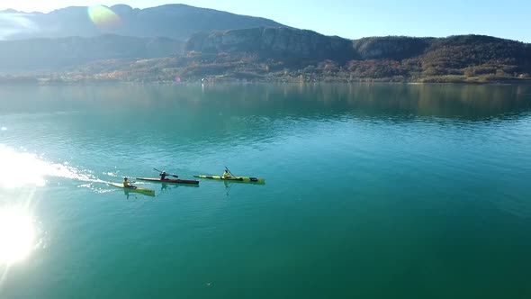 Three kayakers paddle in a scenic mountain lake.