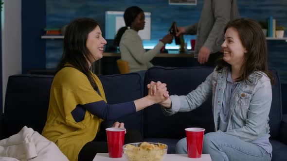 Two Women Hanging Out at Home Party Giving Hight Five While Relaxing on Sofa