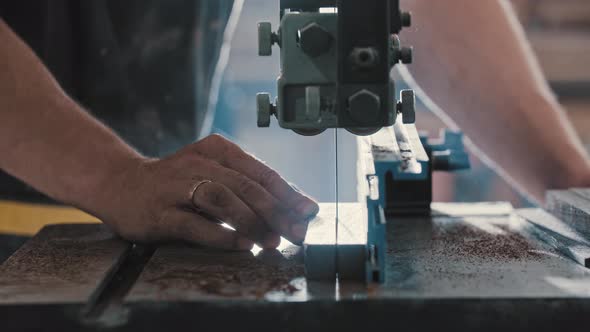 Man in a Carpentry Workshop Cutting a Piece of the Wooden Detail in Two Equal Pieces Using a Cutting