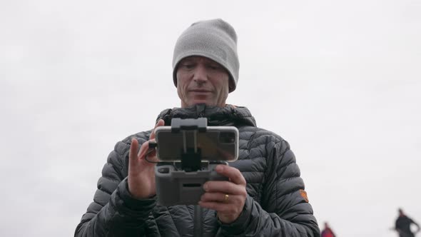 Photographer Using Remote Control Handset To Control Drone