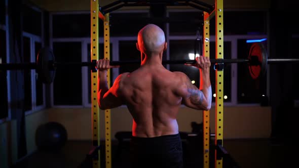 Back View of Shirtless Man Lifting Barbell