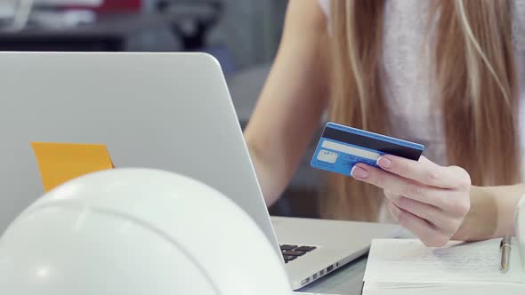 Lady Holding Her Plastic Card in Hand Near Laptop