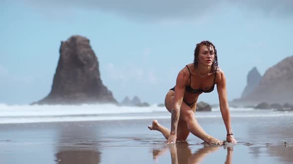 The Girl Is Engaged in Stretching and Gymnastics on the Shore of the Ocean