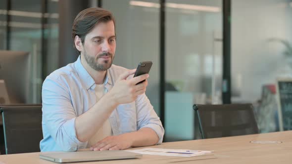 Mature Adult Man Using Smartphone in Office