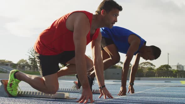 Side view of two athletes beginning race in stadium