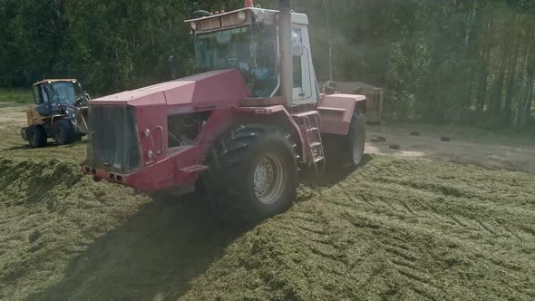 Drone view of tractors tamp the silage in the Silo Trench next to the forest 12