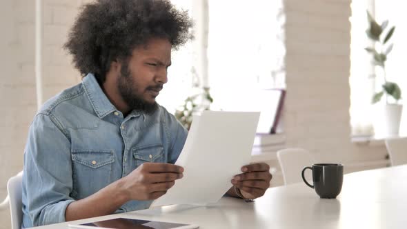 Upset Young African Man Reacting To Loss While Reading Documents