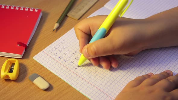 Closeup Pupil's Hands Doing Math in a Notebook