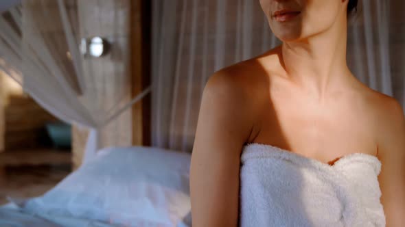 Woman in towel sitting on a canopy bed in cottage 4k