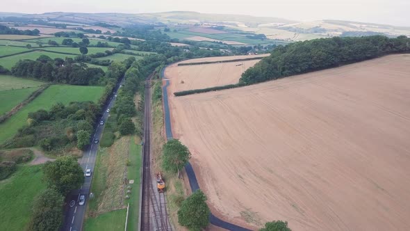 Wide aerial revealing large open english countryside, with a railway track, a road, and pristine gol