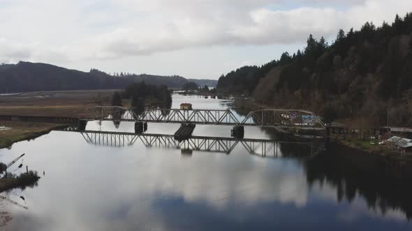 vintage arched railbridge over large Siuslaw river on Cushman town, Oregon. reversing drone view