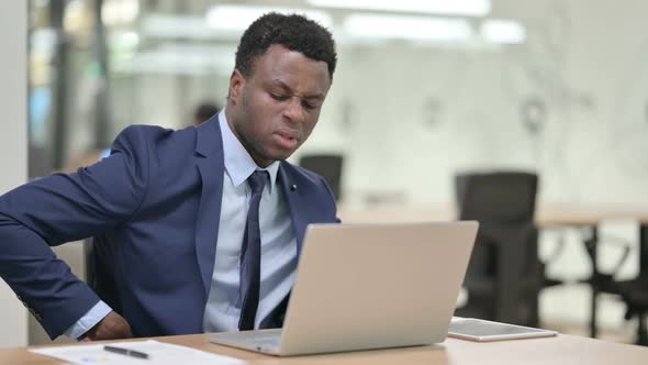 African Businessman Having Back Pain While Using Laptop