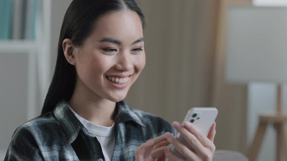 Home Portrait of Asian Woman Girl Blogger Looking at Mobile Phone Screen Smiling Swipe Checking Mail