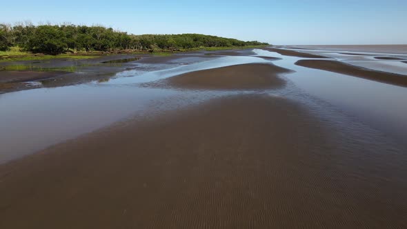 Rising forward aerial of sand banks and woodlands by Rio de la Plata