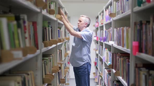 Senior Man with Mustache Taking Book From Shelf in Library