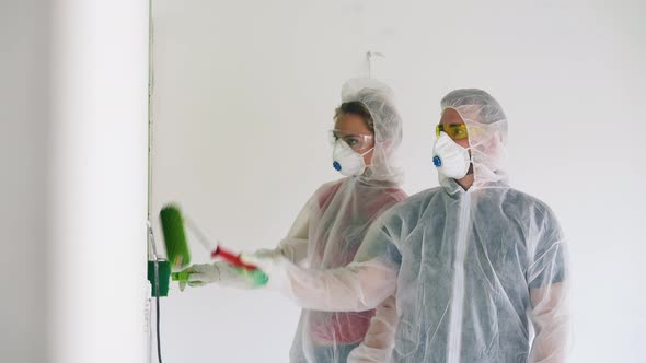 Man and Woman in Transparent Coveralls Paint Room White Wall