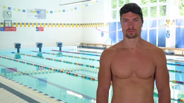 A Professional Swimmer Looks Seriously at the Camera at an Indoor Pool