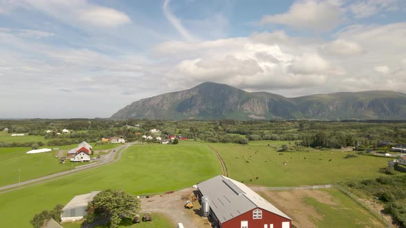 Aerial shot flying over a farm surrounded by mountains and fields in Norway