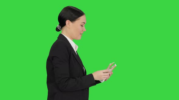 Happy Business Woman Counting Money While Walking on a Green Screen, Chroma Key.