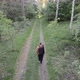 Aerial Drone View Following Young Caucasian Man with Backpack Walking through Forest - VideoHive Item for Sale