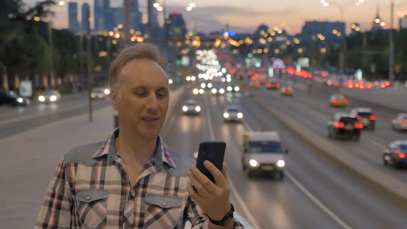 Man Makes Selfie Against Wide Street in Evening City