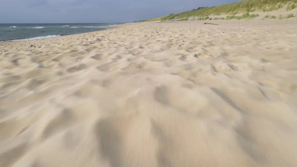 AERIAL: Flying Very Close to the Sand Beach Ground with Water Waves Crashing on the Shore