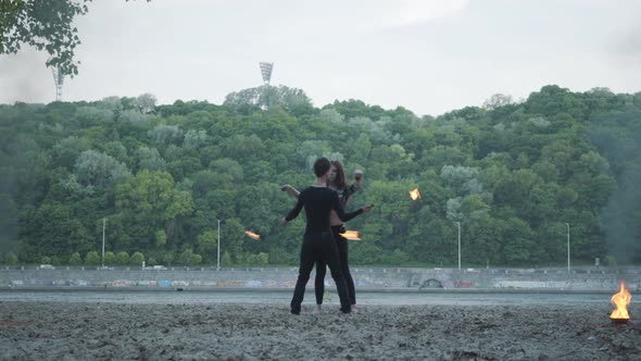 Young Beautiful Girl and Handsome Man in Black Clothes Performing Show with Flame Standing on the