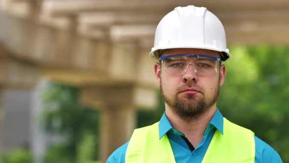 Closeup Portrait of a Young Master Builder in a Protective Hard Hat Looking at the Camera Standing