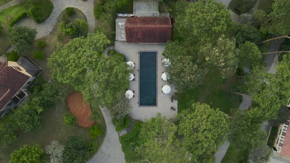Aerial drone flying above of a beautiful swimming pool under sunshine reveal landscape of resort on