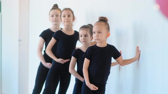 Young Girls Lean on White Wall and Practice Ballet Moves