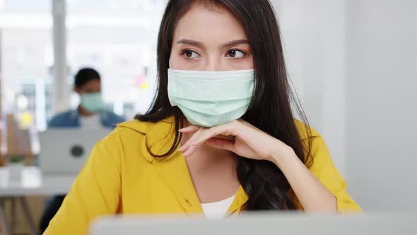 Asia women wear face mask using laptop hard work at new normal home office