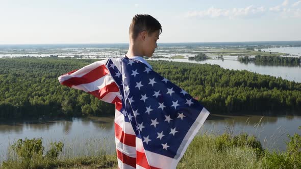 Blonde Boy Waving National USA Flag Outdoors Over Blue Sky at the River Bank