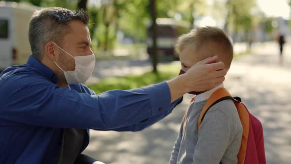 Close Up of the Disabled Father in Mask Sitting on the Wheel Chair Wearing Mask to His Son Before