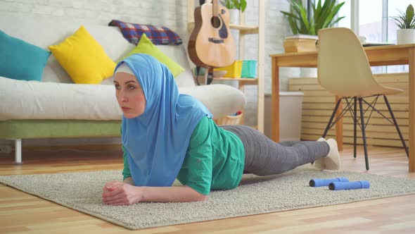 Sporty Muslim Woman in Hijab Makes Plank in a Modern Apartment