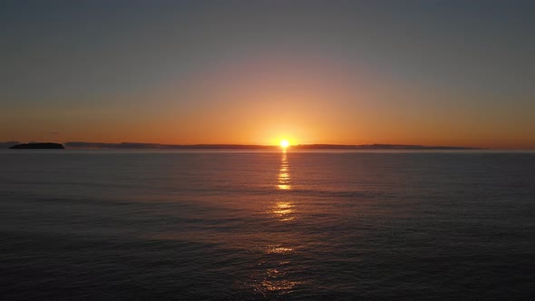 Peaceful sunrise over calm ocean waves cast a golden glow at Matadouro beach.