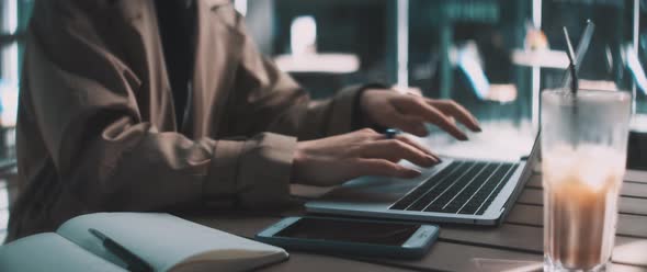 Young business woman typing on laptop sitting outside