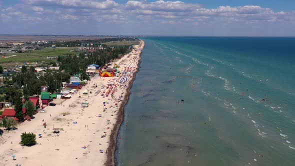 Beautiful flight in summer over the beach. People are resting near the sea.