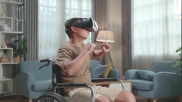 Young Asian Boy Sitting In A Wheelchair While Wearing Virtual Reality Goggles And Dancing At Home