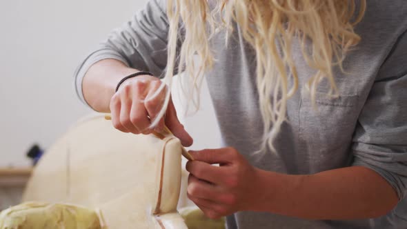 A Caucasian male surfboard maker polishing a wooden surfboard edge