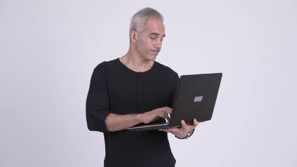 Happy Handsome Persian Man Thinking While Using Laptop