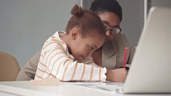 Little Girl and Teacher Having Lesson in Classroom