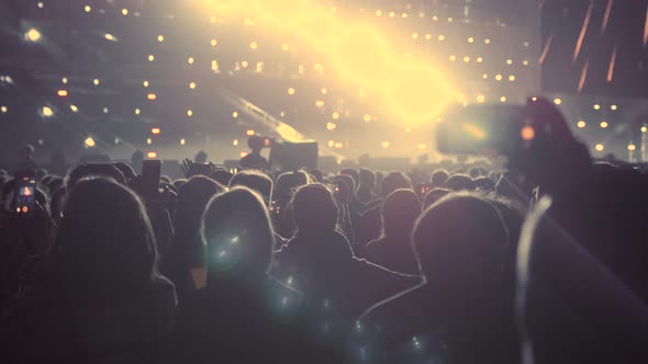 Audience with Hands Raised at a Music Festival and Lights Streaming Down From Above the Stage. A Lot