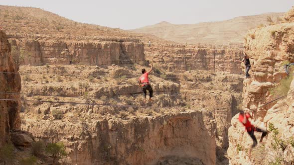 A man balances while tightrope walking and slacklining across a canyon